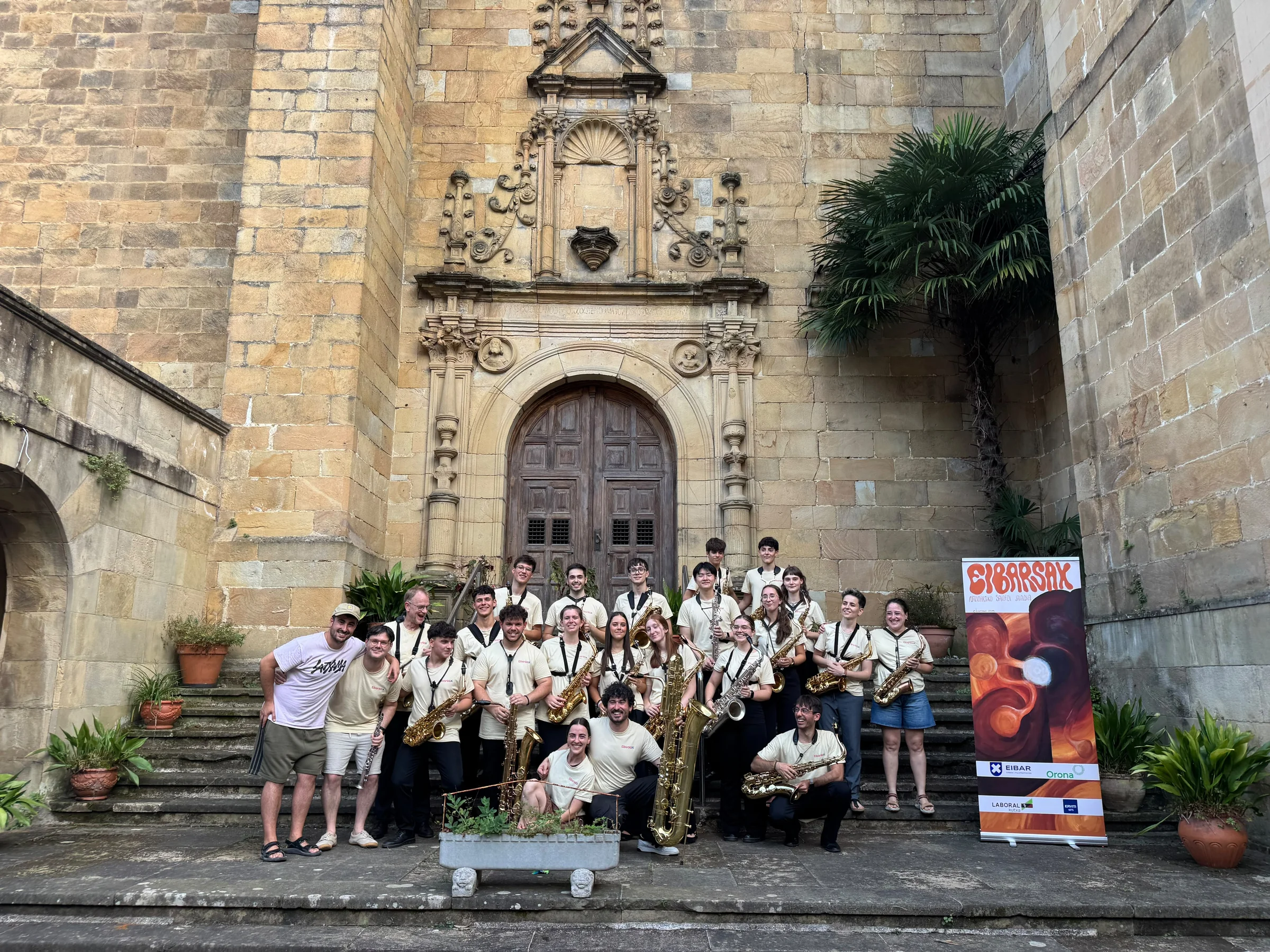 Eibarsax 2026 participants with their saxophones on the steps, beside the festival banner.